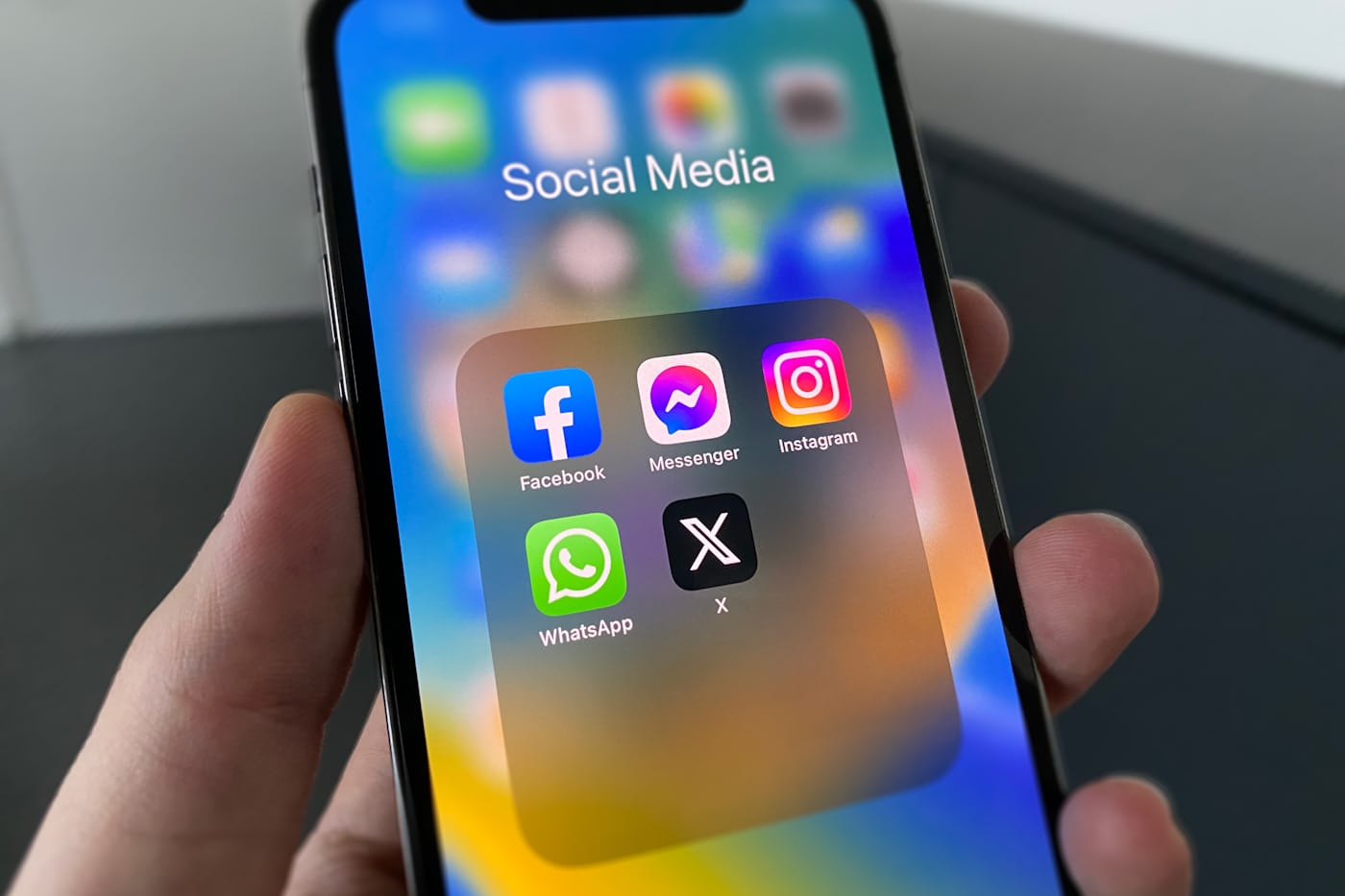 Mano sosteniendo un móvil con una carpeta de aplicaciones de redes sociales abierta